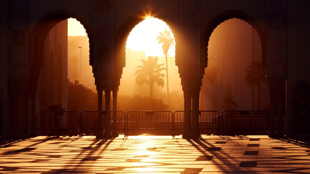 Sunset light shining through ornate arches in North Africa.