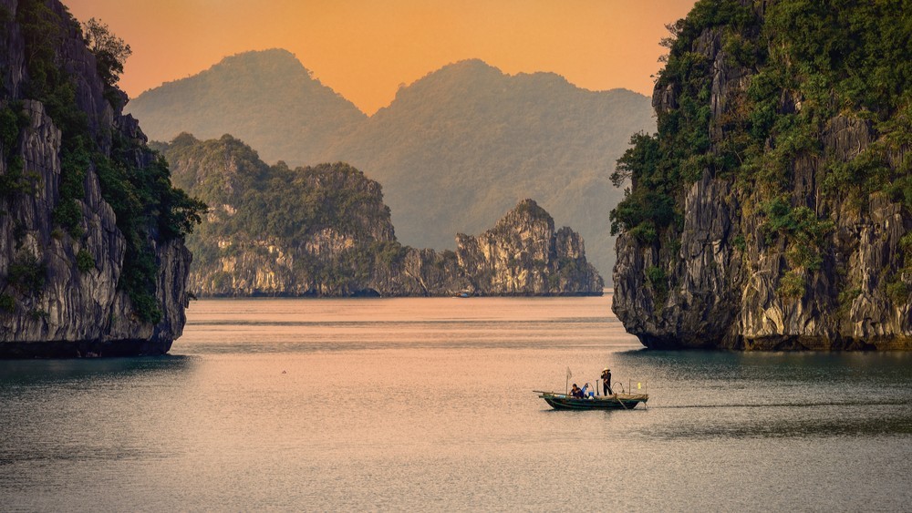 Limestone karsts rising from the water at sunset in Ha Long Bay, Vietnam.