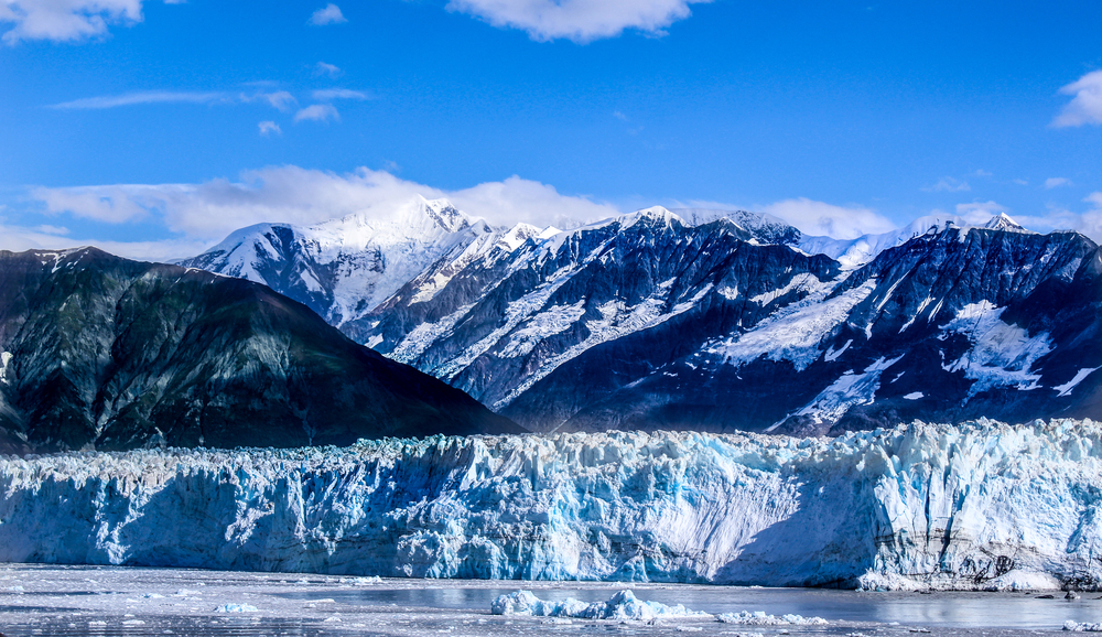 Hubbard Glacier’s massive blue ice face against snowcapped mountains under a clear Alaska sky.