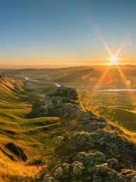 sun coming up over rolling green hills of New Zealand