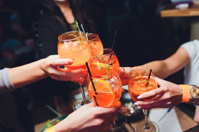 Friends raising Aperol Spritzes for an Italian aperitivo