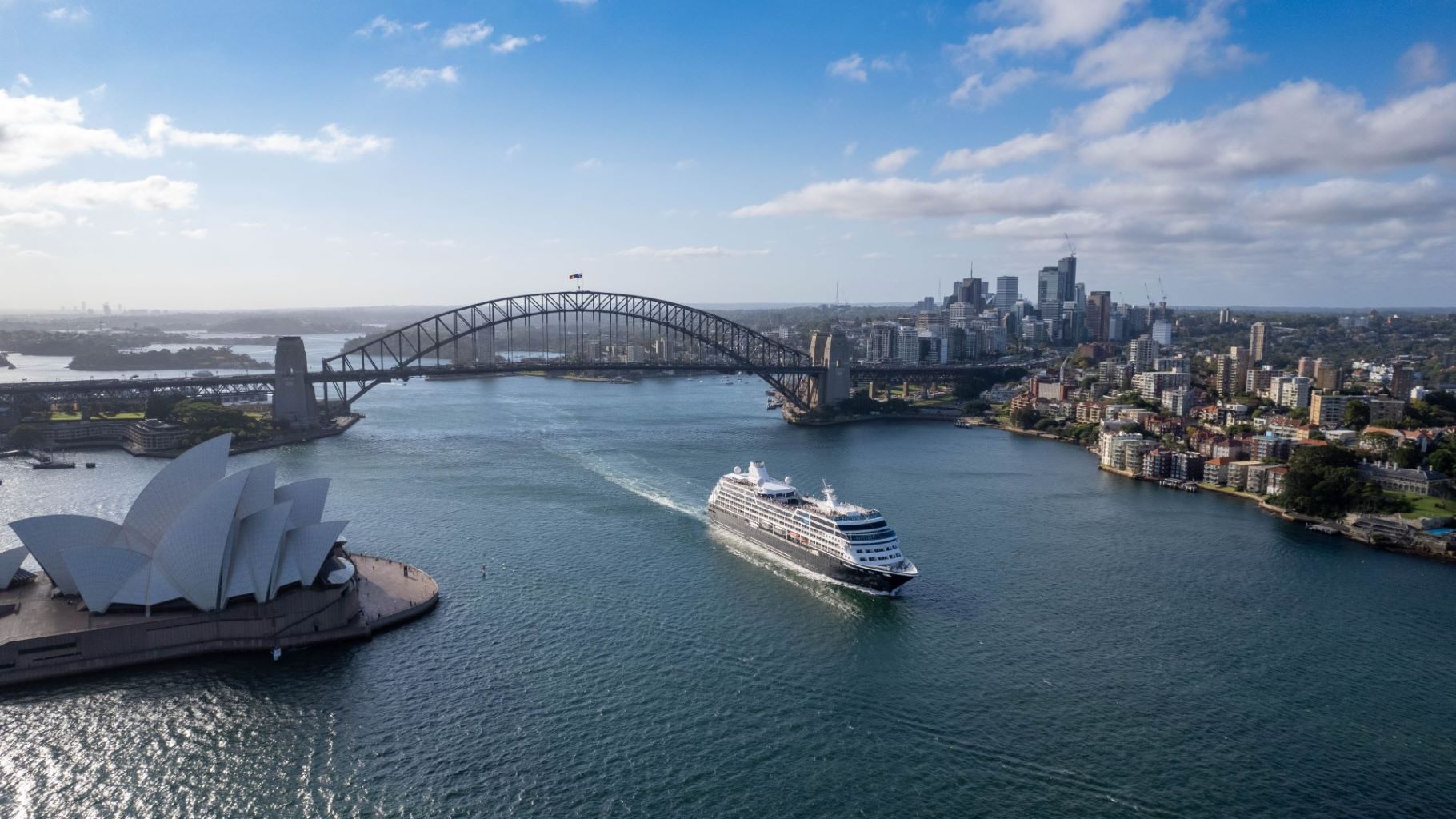 cruise ship passing under bridge in afternoon