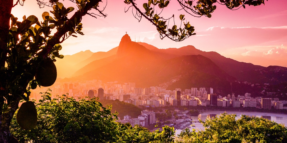 seaside city in front of mountains at sunset