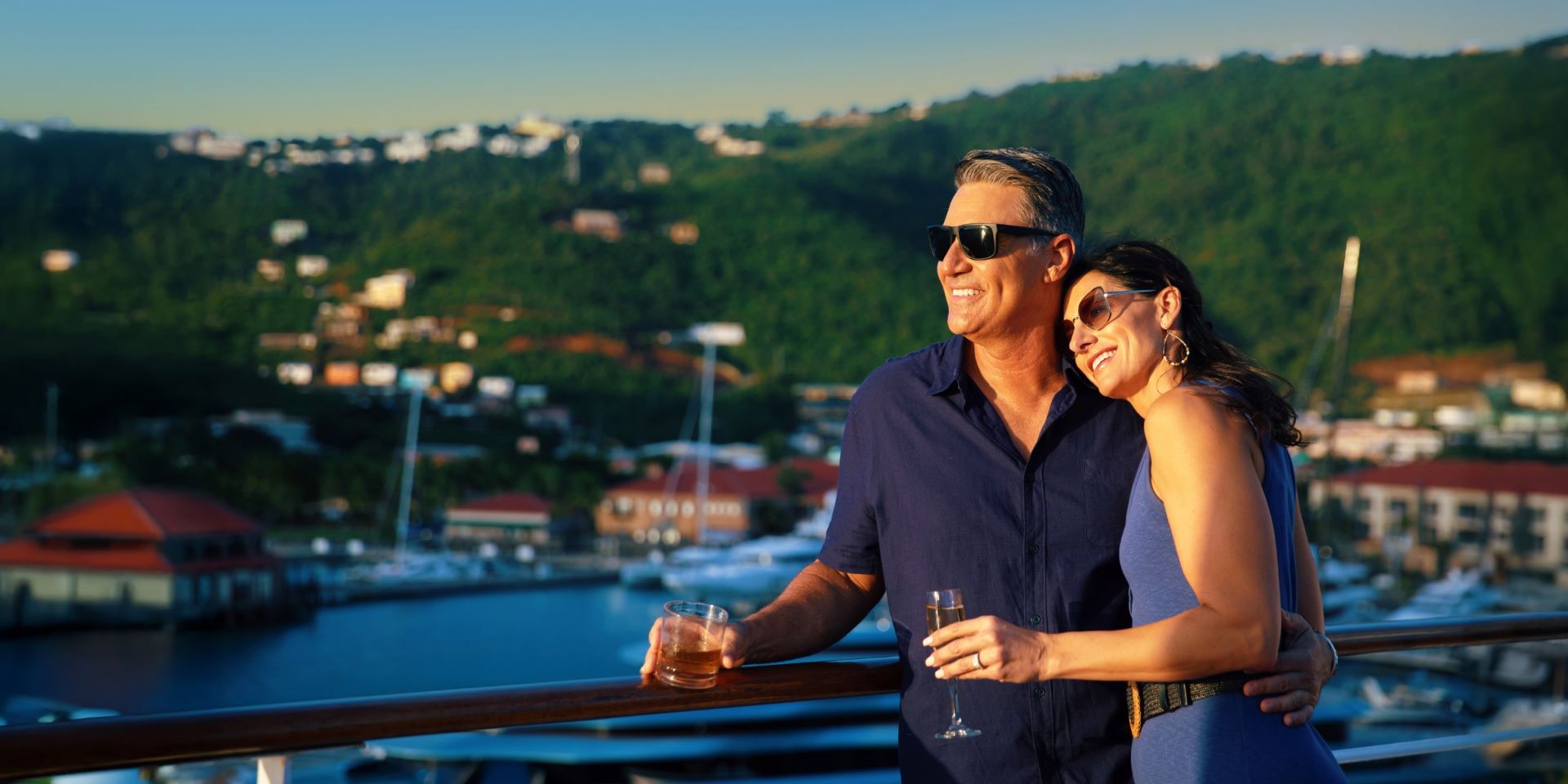 embraced couple with drinks enjoying view from cruise ship deck