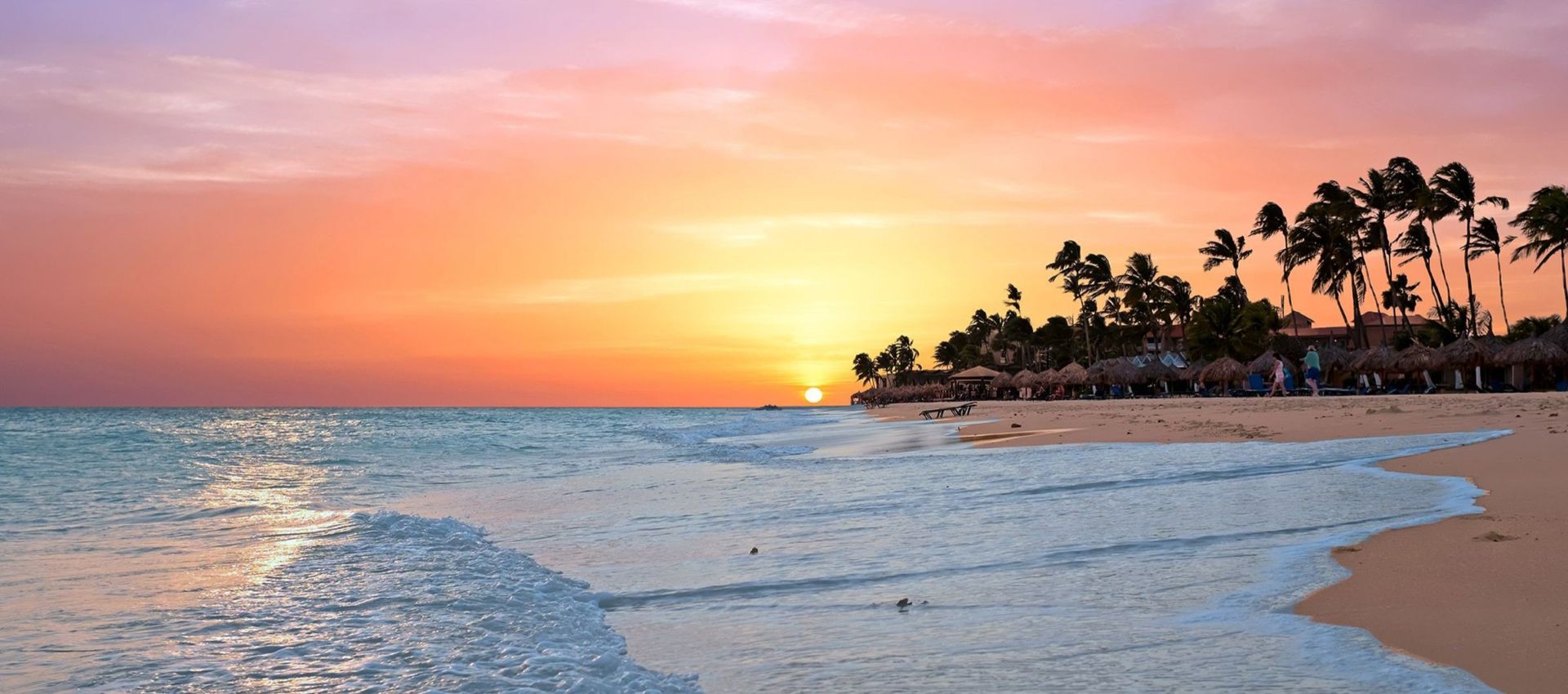 Golden sunset along Aruba’s palm-lined beach.