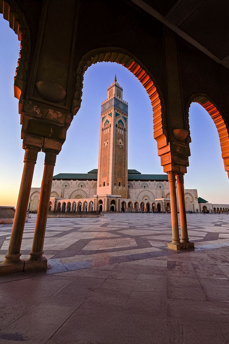 Hassan II Mosque in Casablanca, Morocco, framed by ornate archways at sunset.