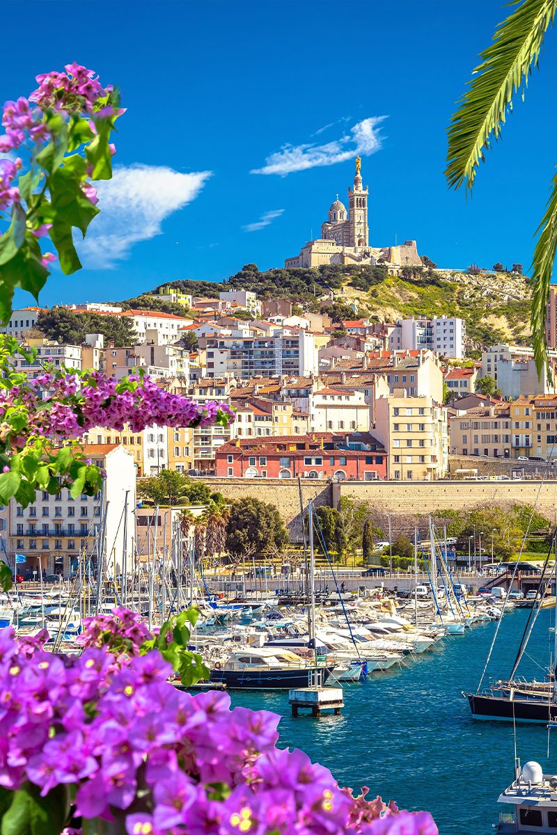 Panoramic view of Marseille’s Old Port with boats and Notre-Dame de la Garde on the hill.