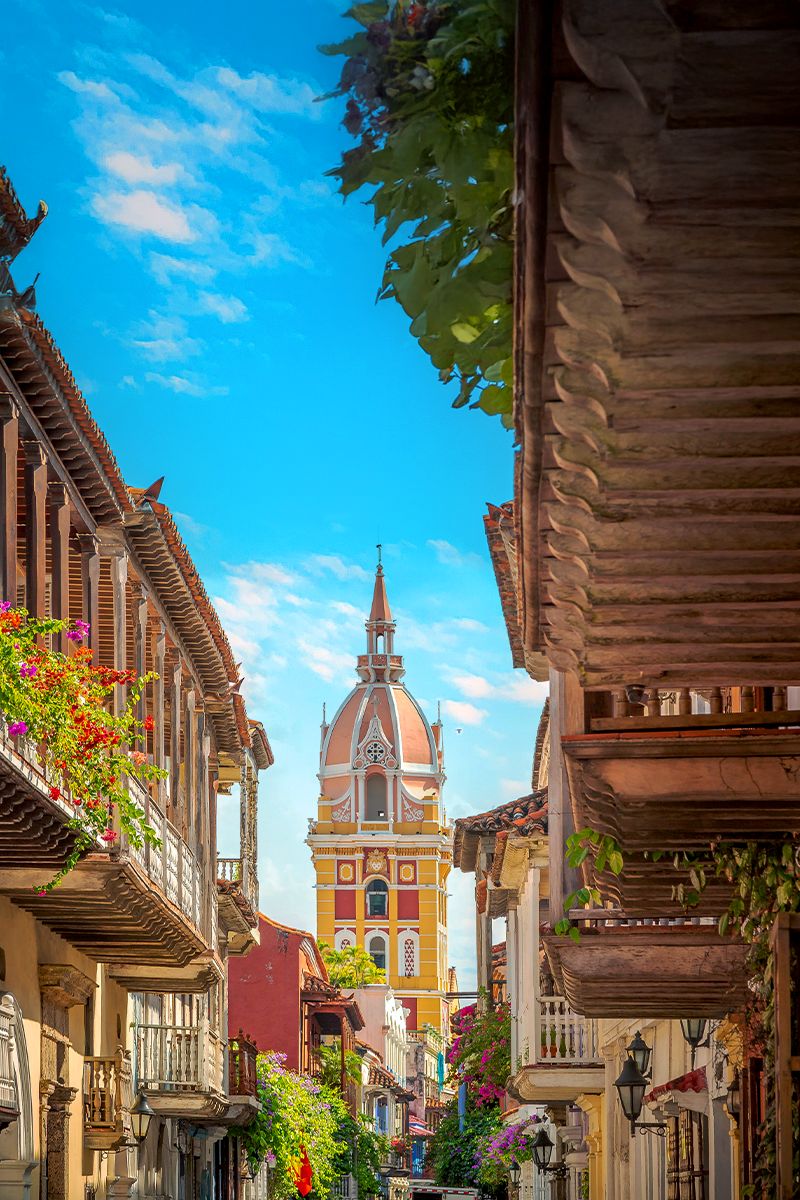 Colorful colonial street in Cartagena’s Old Town with a view of the iconic cathedral tower.