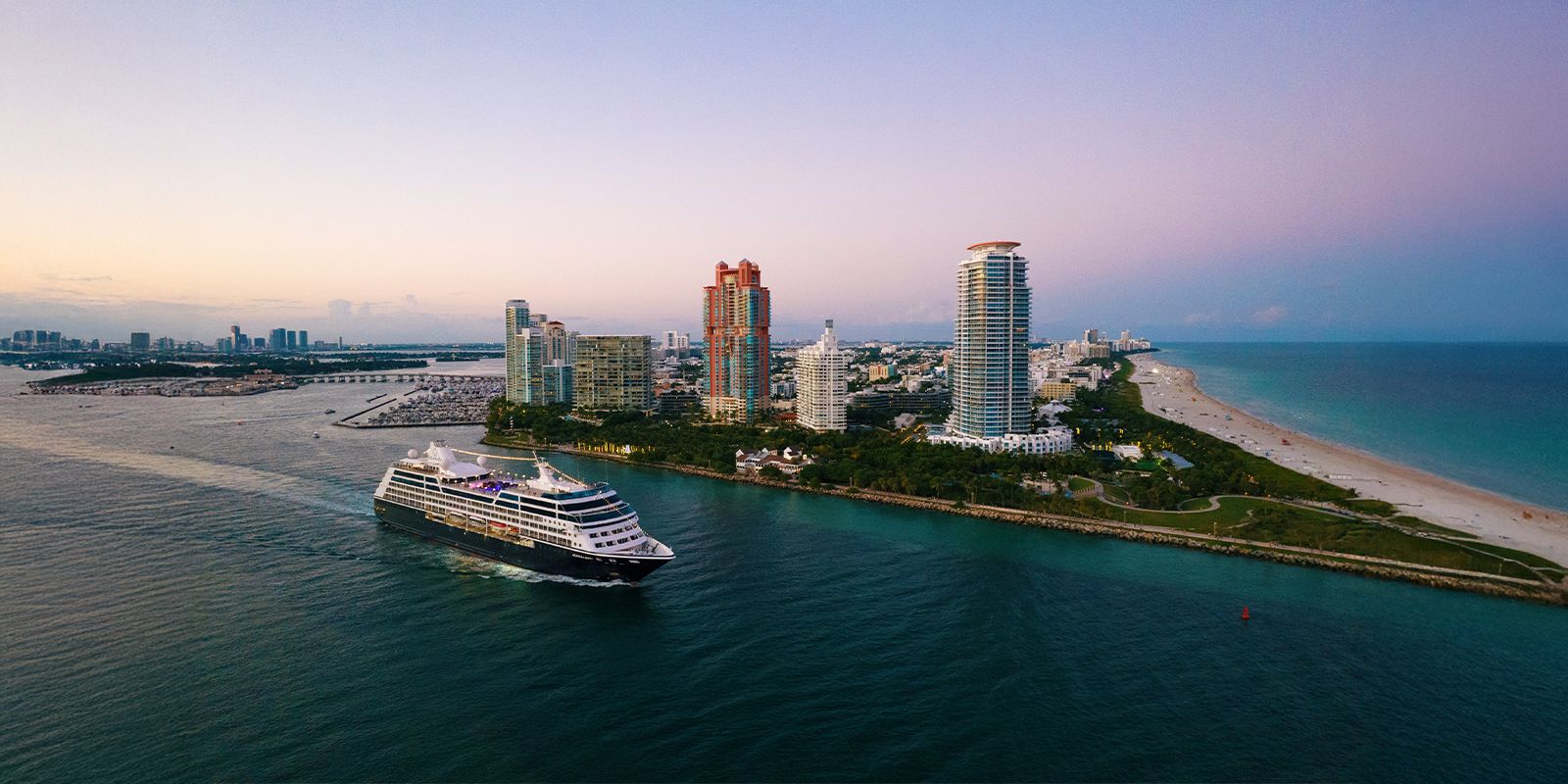 Miami, Florida skyline and coastline with a cruise ship departing at dusk.