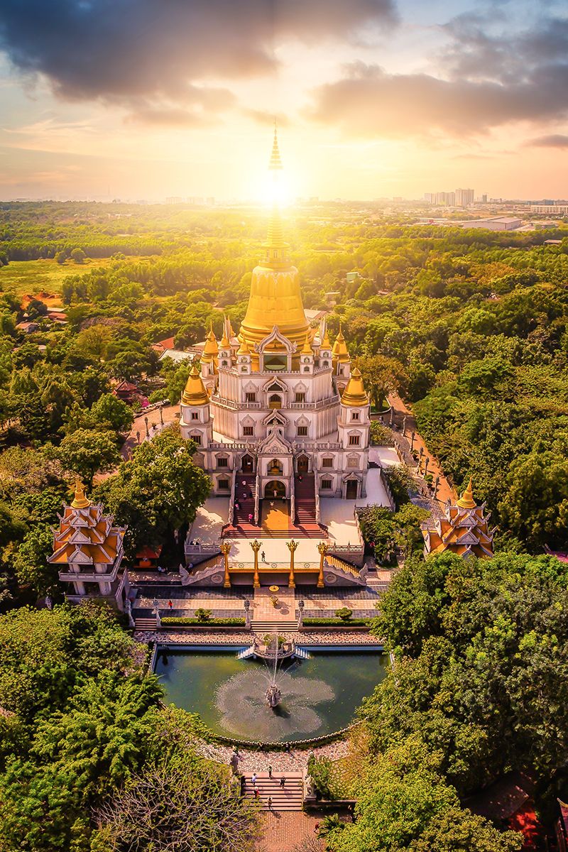 Golden sunrise over the ornate Buu Long Pagoda surrounded by lush greenery in Ho Chi Minh City.