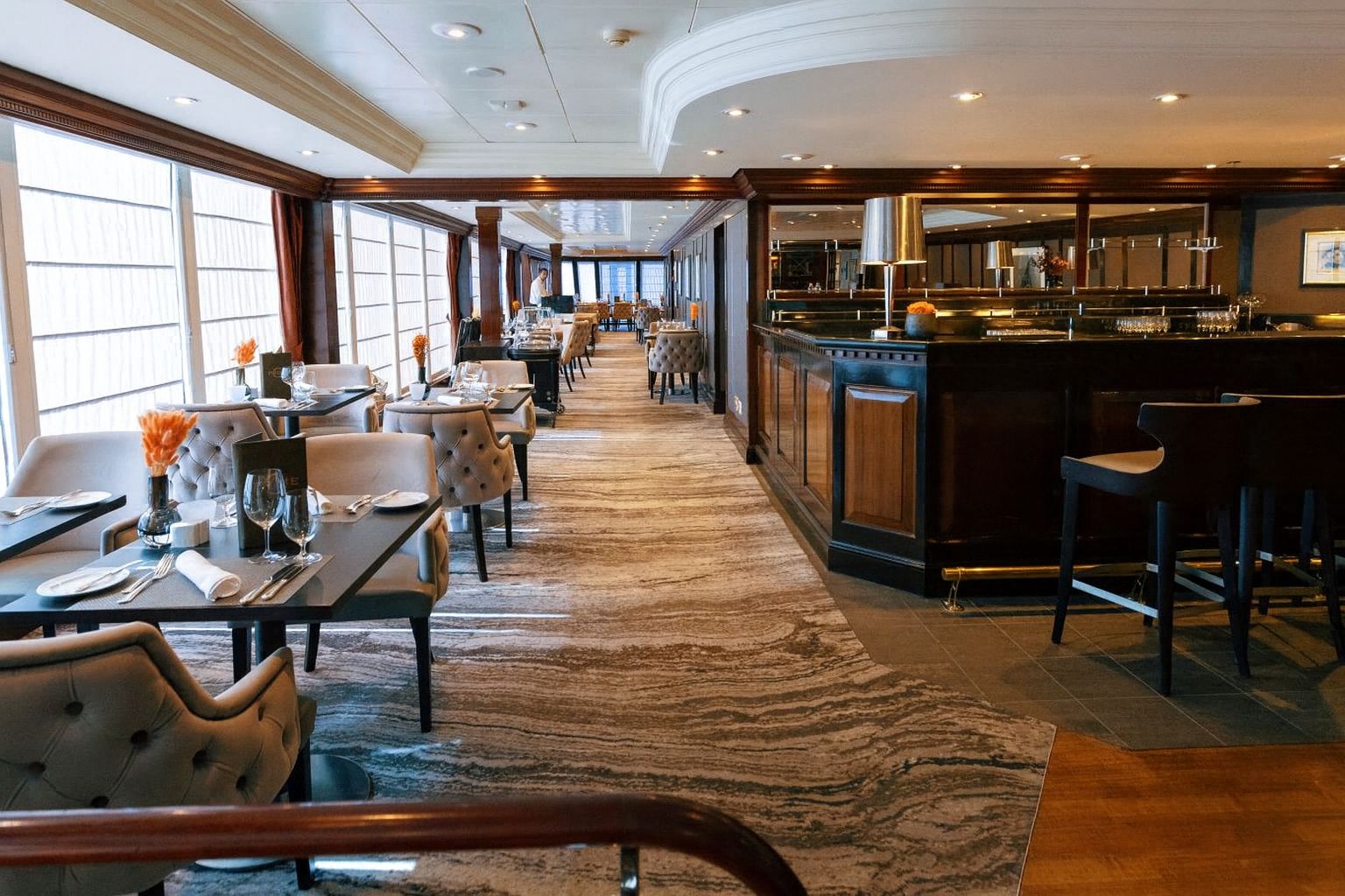 Prime C specialty restaurant featuring ocean-view windows, tufted seating, and a warm wood-accented bar on board Azamara.