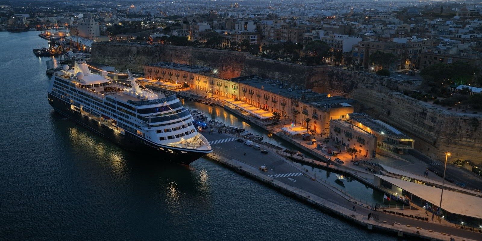 cruise ship in port at night in front of mountain range