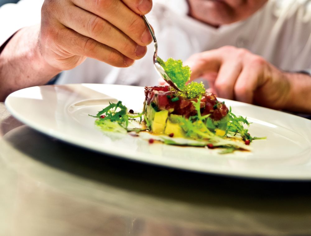 chef adding garnish to dinner plate