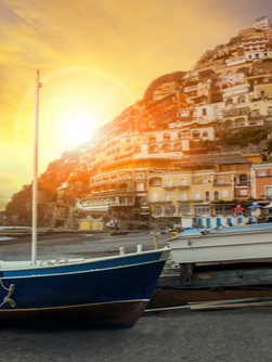 small fishing boat docked at foot of seaside village at sunrise