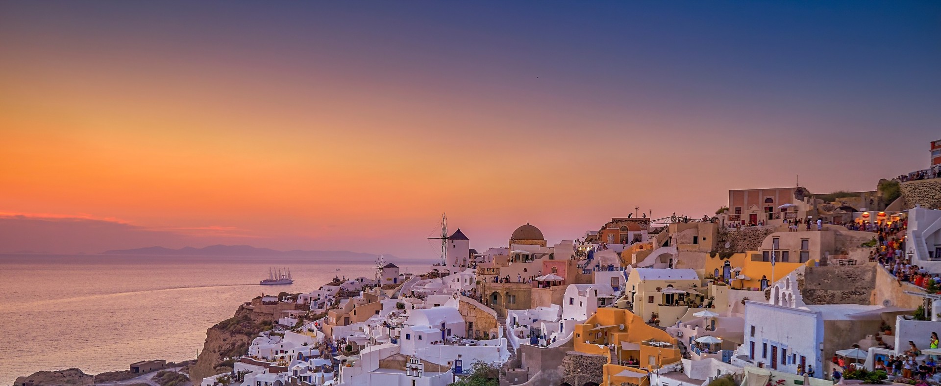 Santorini’s whitewashed cliffside at sunset overlooking the Aegean Sea.