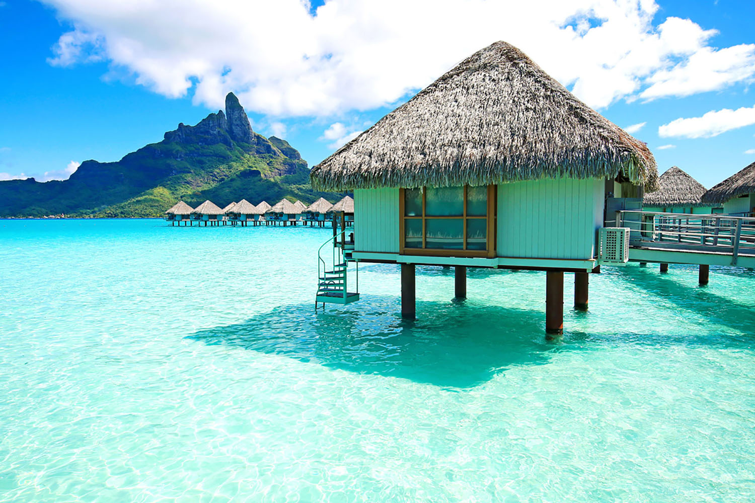 Grass-roofed huts on the beach in Bora Bora, French Polynesia.