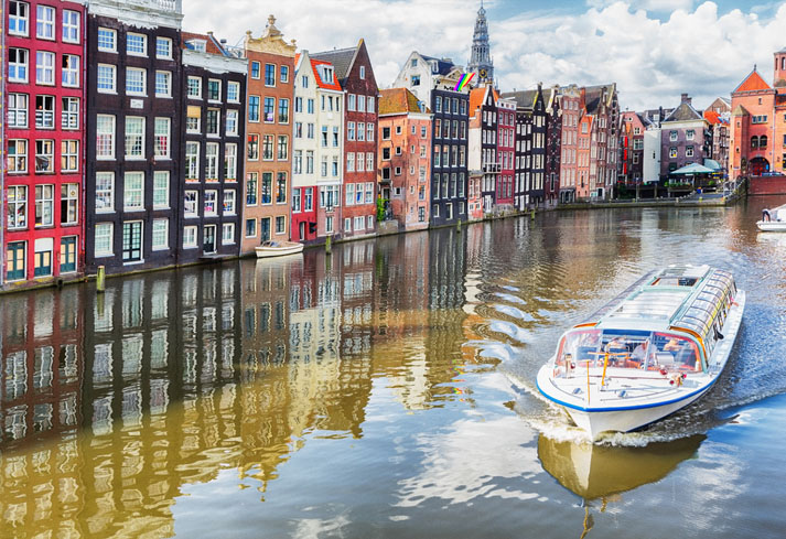 Colorful houses, canal and a classical tour boat of Amsterdam