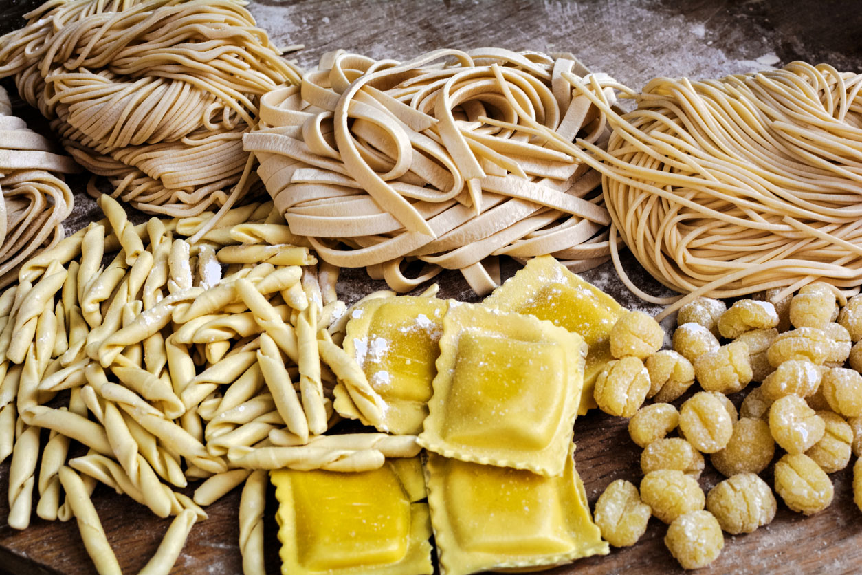 hotograph of flour blushed spaghetti, tagliatelle, fettuccine, linguine, ravioli on an old wooden table