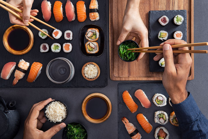 Top view of couple hands eating sushi food at Japanese restaurant