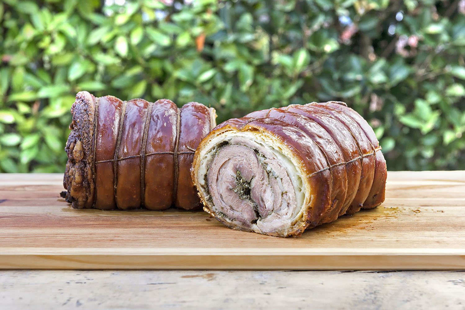 Porchetta cut in half on chopping board