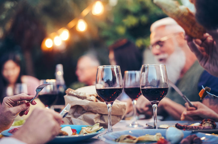People gathered around a dinner table with glasses of wine