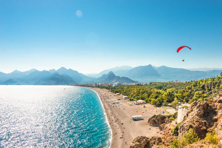 Panoramic view of Antalya seacoast and beach with a paraglider in the background.