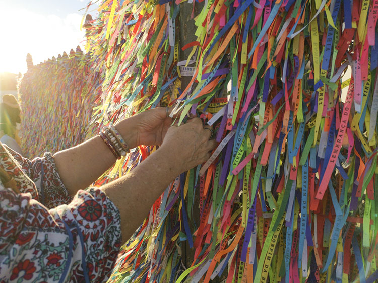 Hands tying Colorful ribbons on grid in front of Bonfim Church in Salvador, Bahia, Brazil
