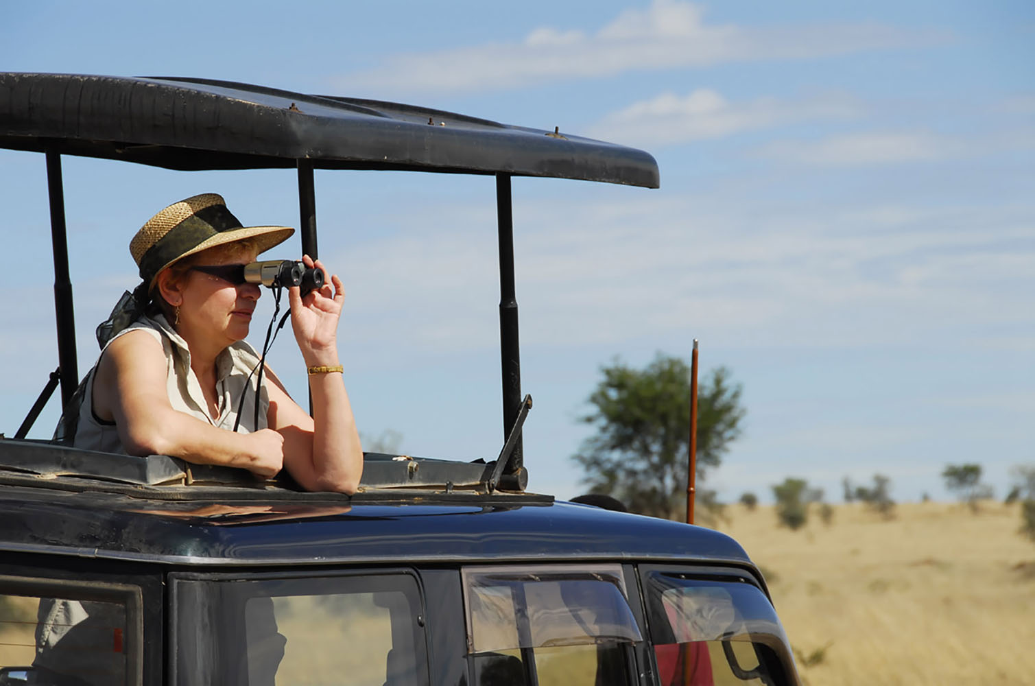 A woman spotting wildlife with binoculars during wildlife safari