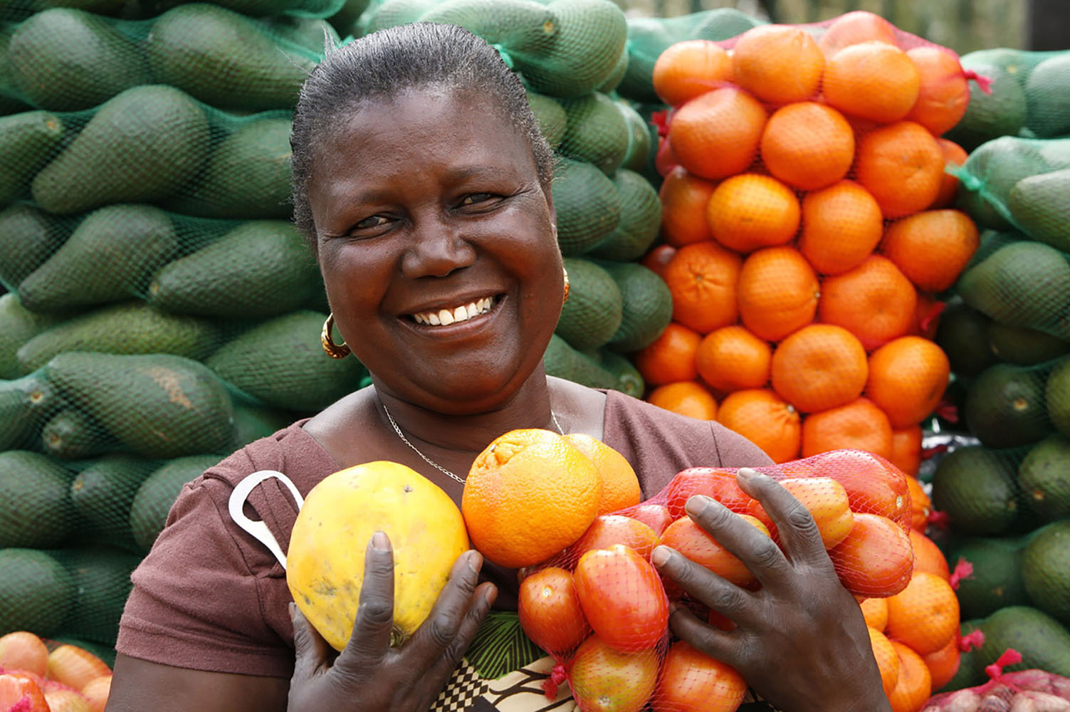 A fruit and vegetable seller poses in front of her produce.