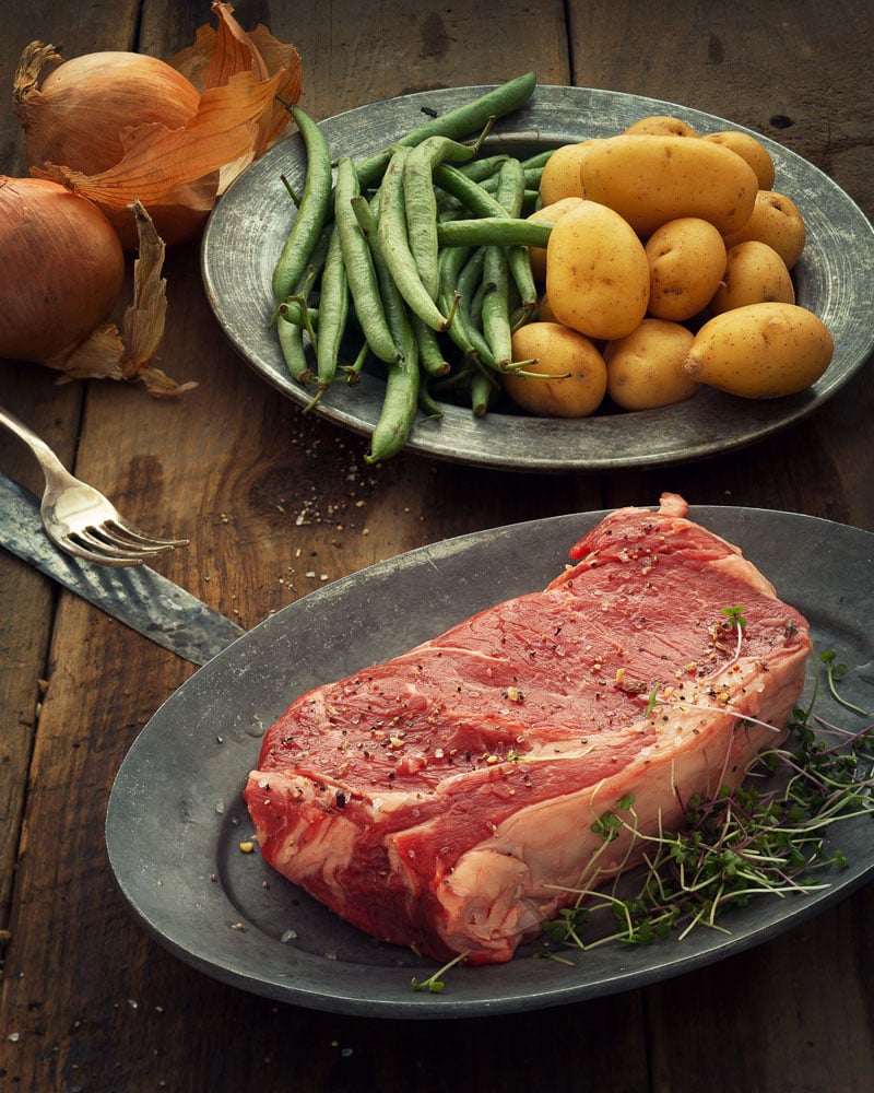 rib-eye steak, potatoes and green beans on vintage metal plates