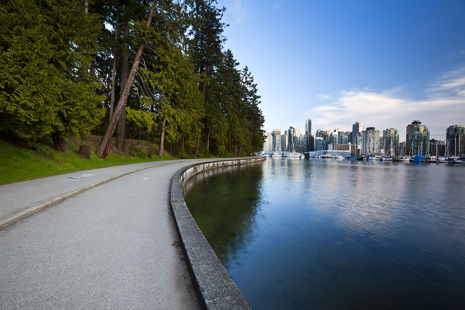 The Stanley Park Seawall in Vancouver with a view of the city skyline.