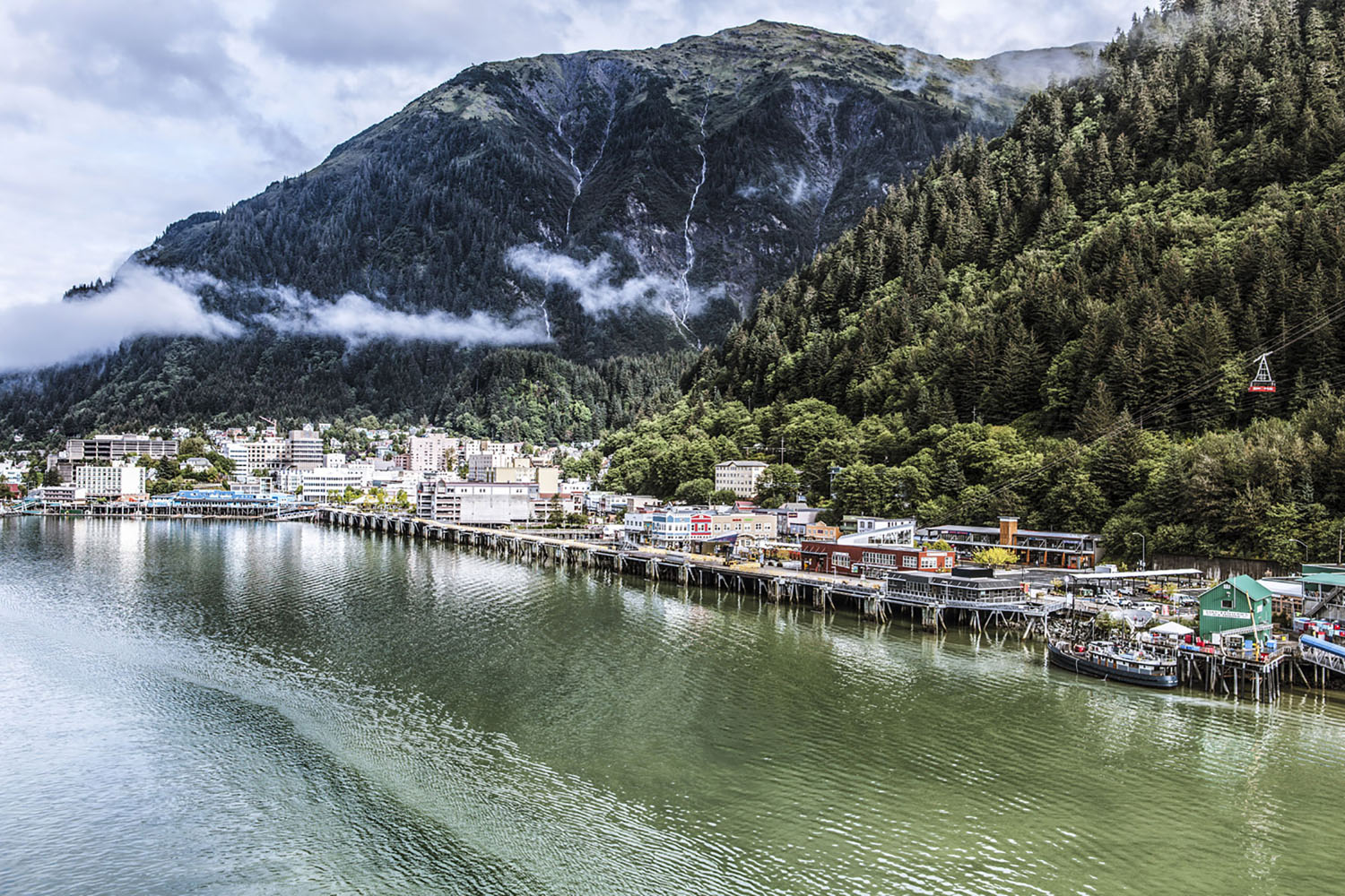 The waterfront of Juneau, Alaska is surrounded by lush green mountains.