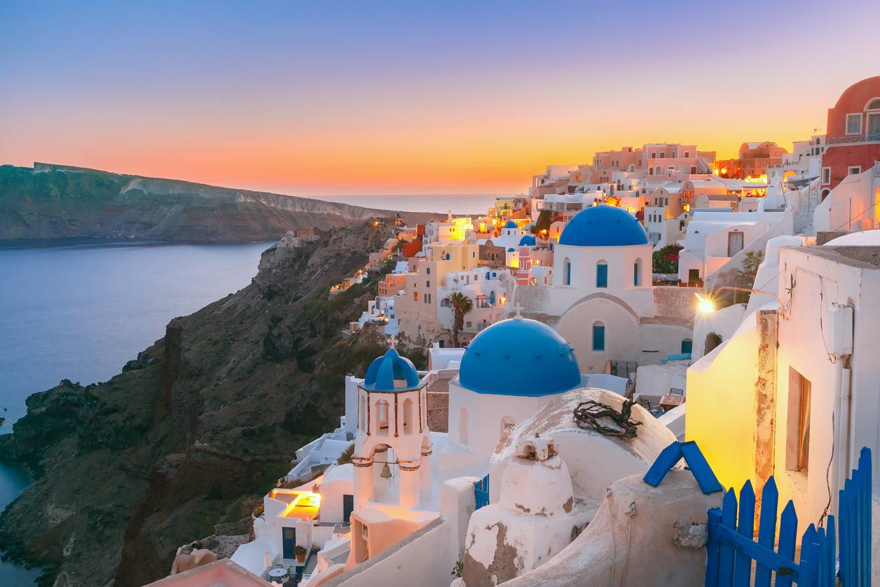 Picturesque view, Old Town of Oia or Ia on the island Santorini, white houses and church with blue domes at sunset, Greece