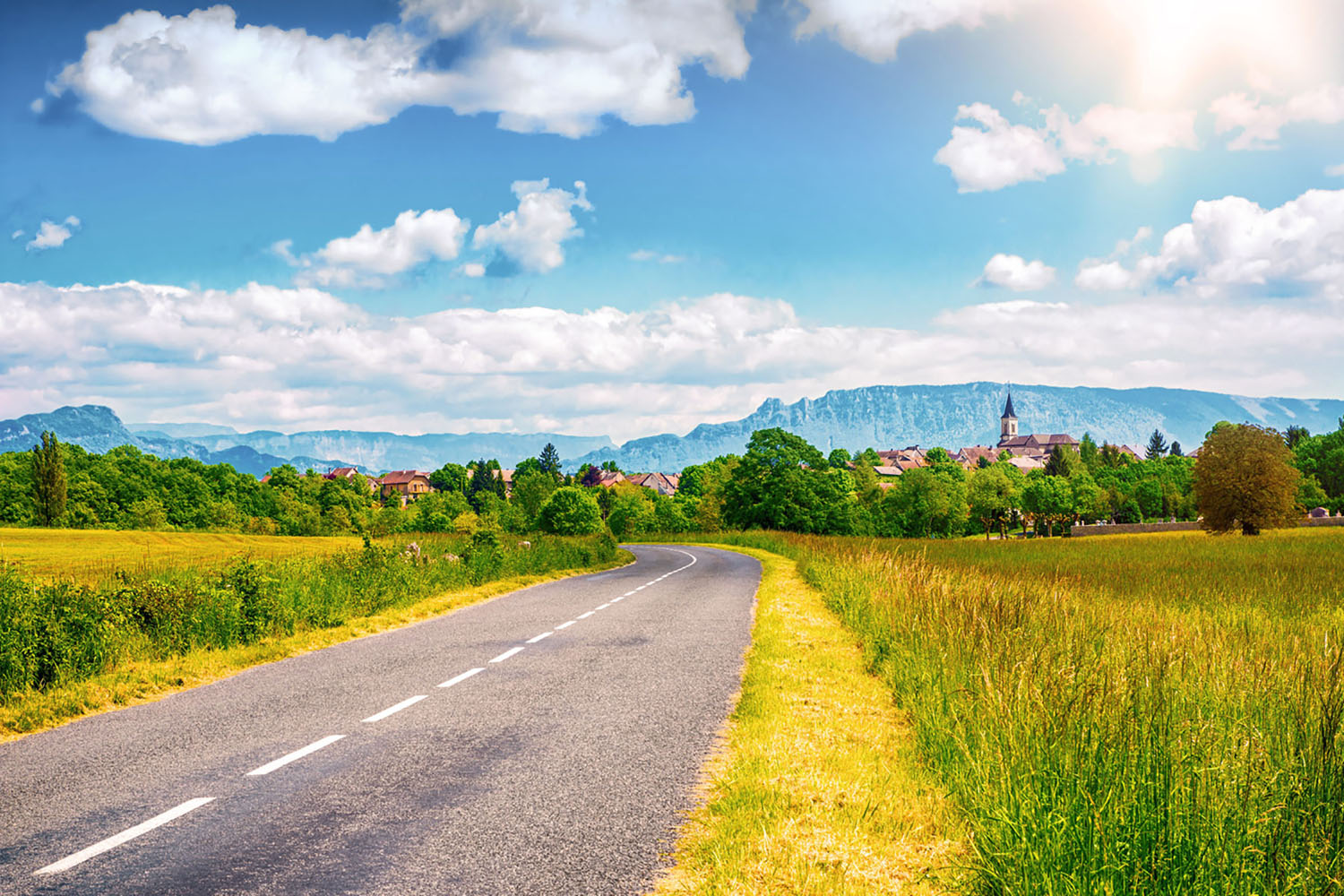 An empty road winding through the French countryside.