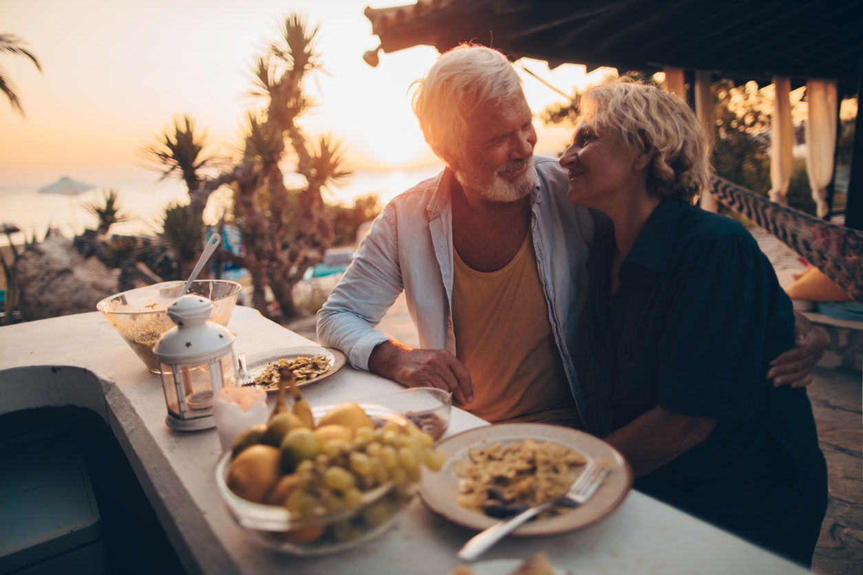Senior couple having a romantic dinner outdoors at sunset in Greece