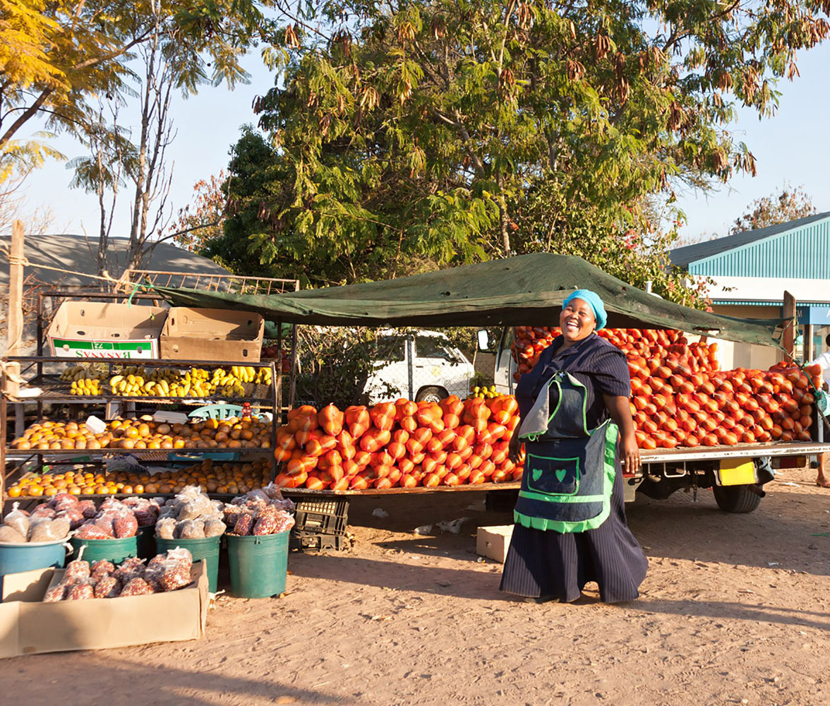 An African woman street vendor smiles in front of her goods
