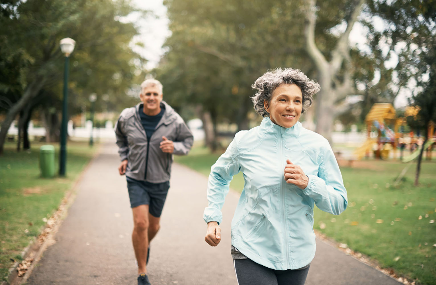 A man and woman jog together through a park