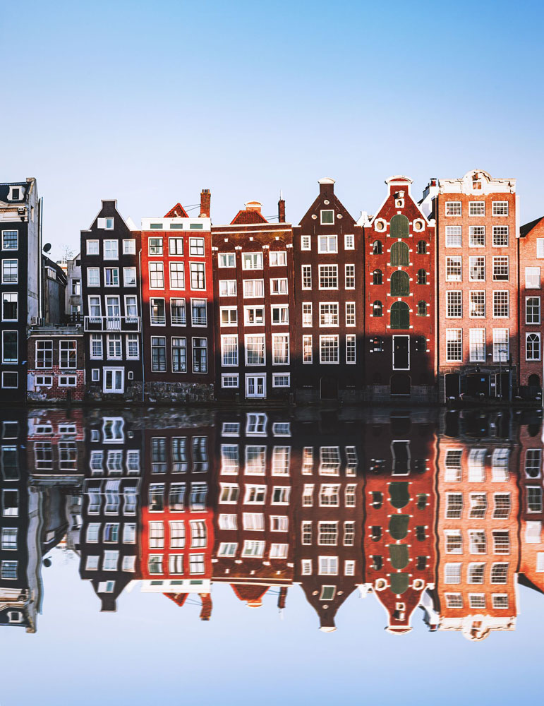 Crooked houses in Amsterdam reflect off the water