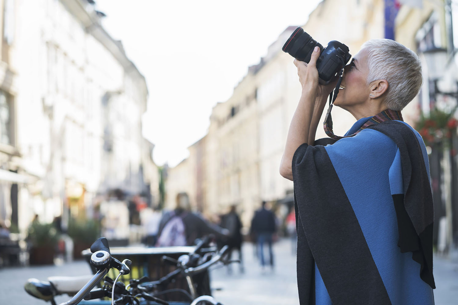A woman takes a photo of a building.