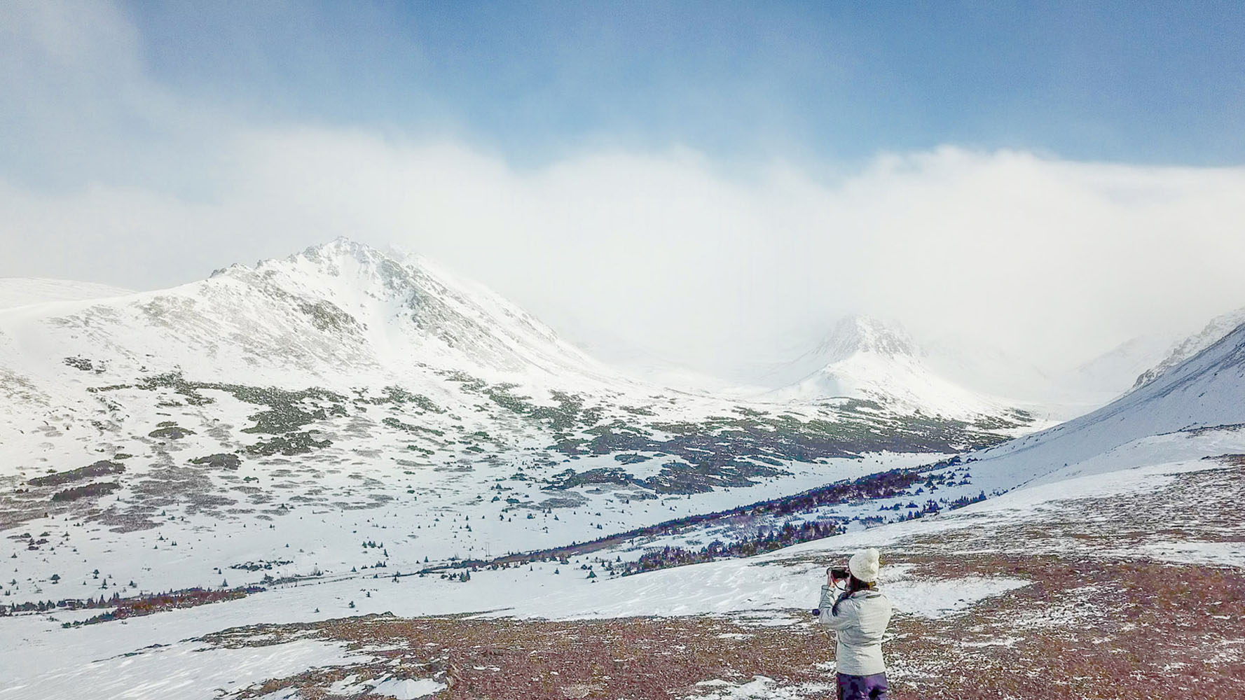 A woman takes a photo of the landscape in Alaska.