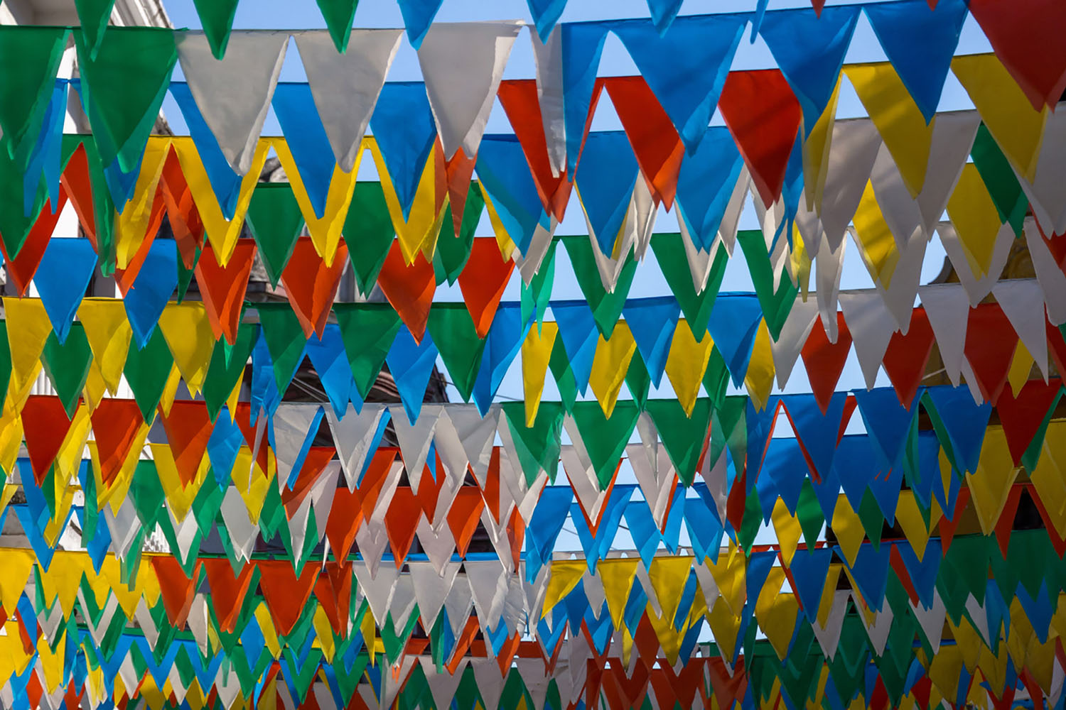 Bright coloured triangular flags hang closely together from lines in Cartagena, Colombia
