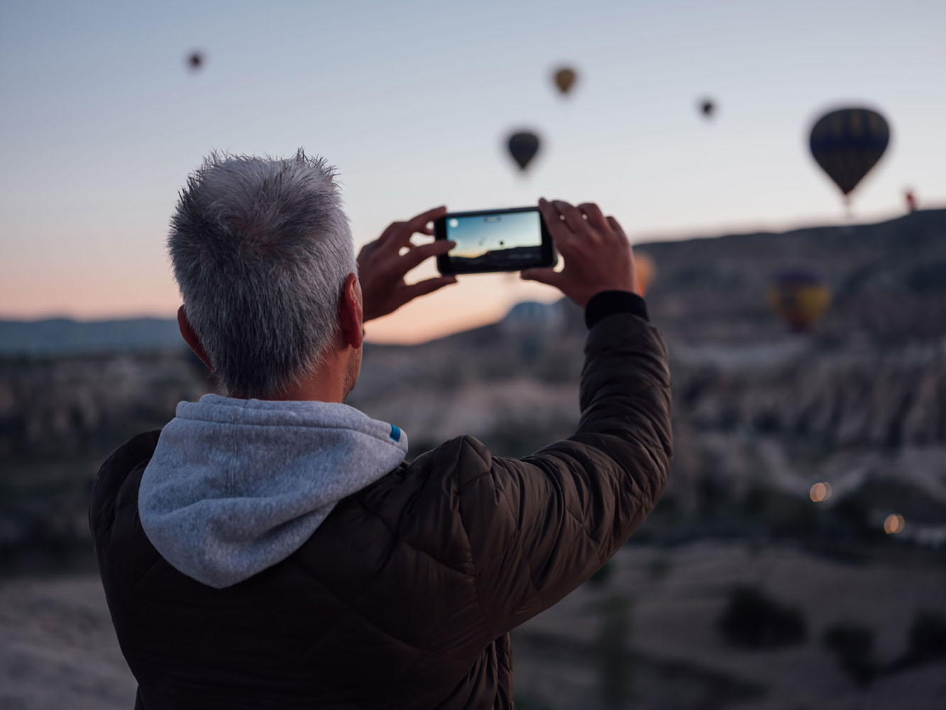 A man takes photos of hot air balloons using his phone