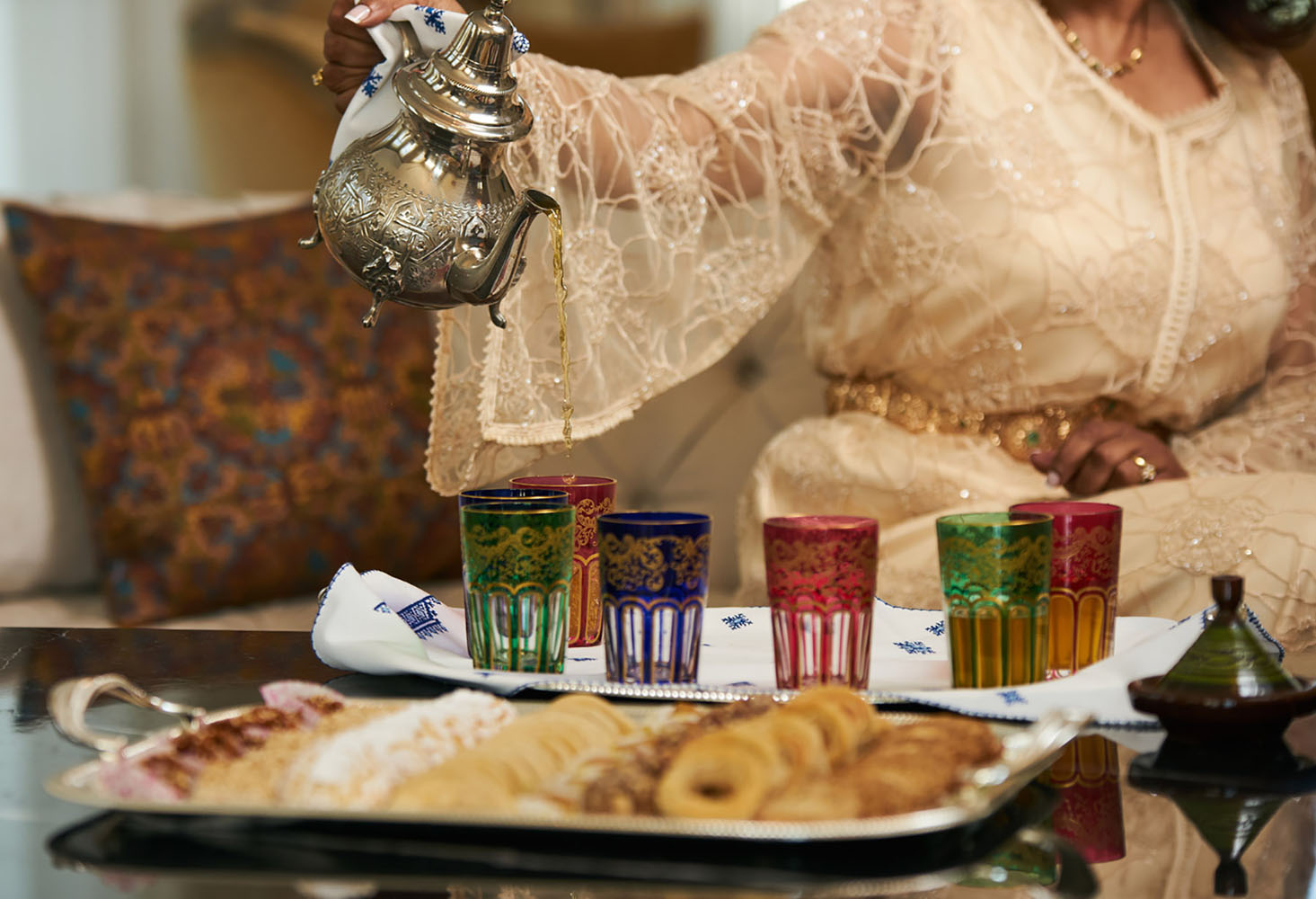 A woman Pours Moroccan Tea from Traditional moroccan Teapot into cups