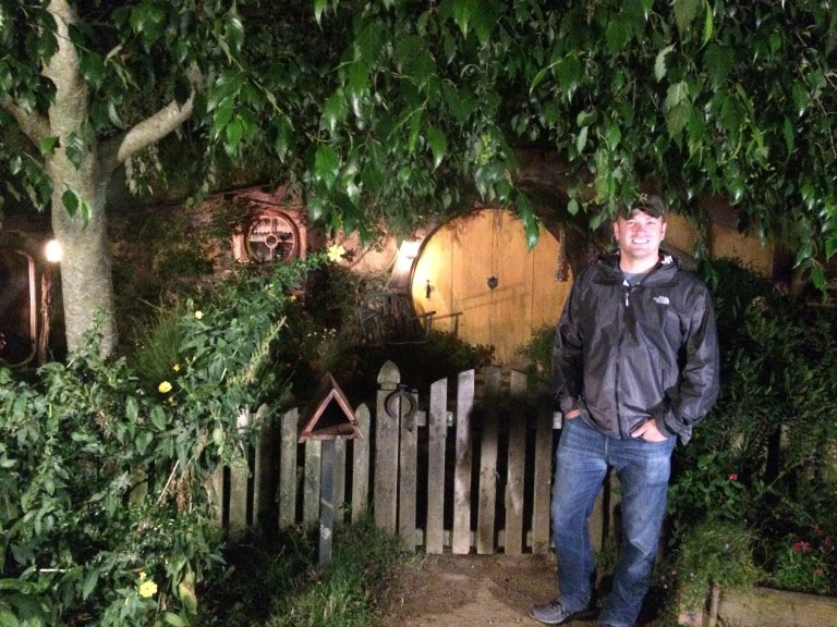 A tourist standing by a Hobbit Hole on the Hobbiton movie set