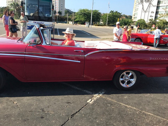 A woman in a red classic car in Cuba.