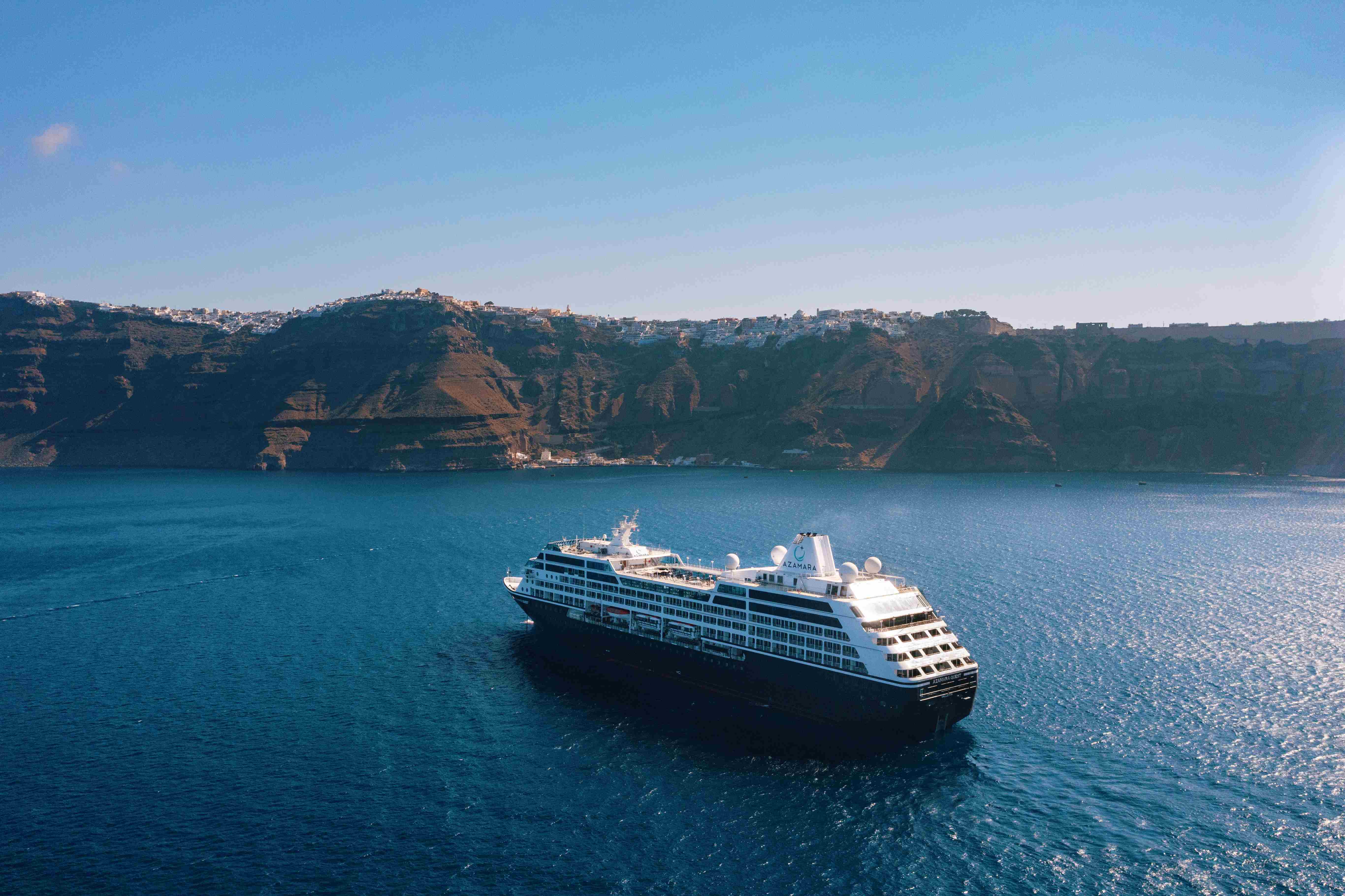 An Azamara ship sails with cliffs in the background