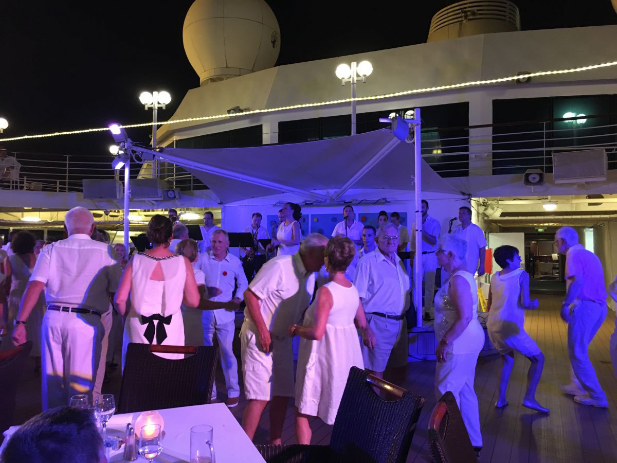 People dancing to the Azamara Quest Band on the deck of a cruise ship