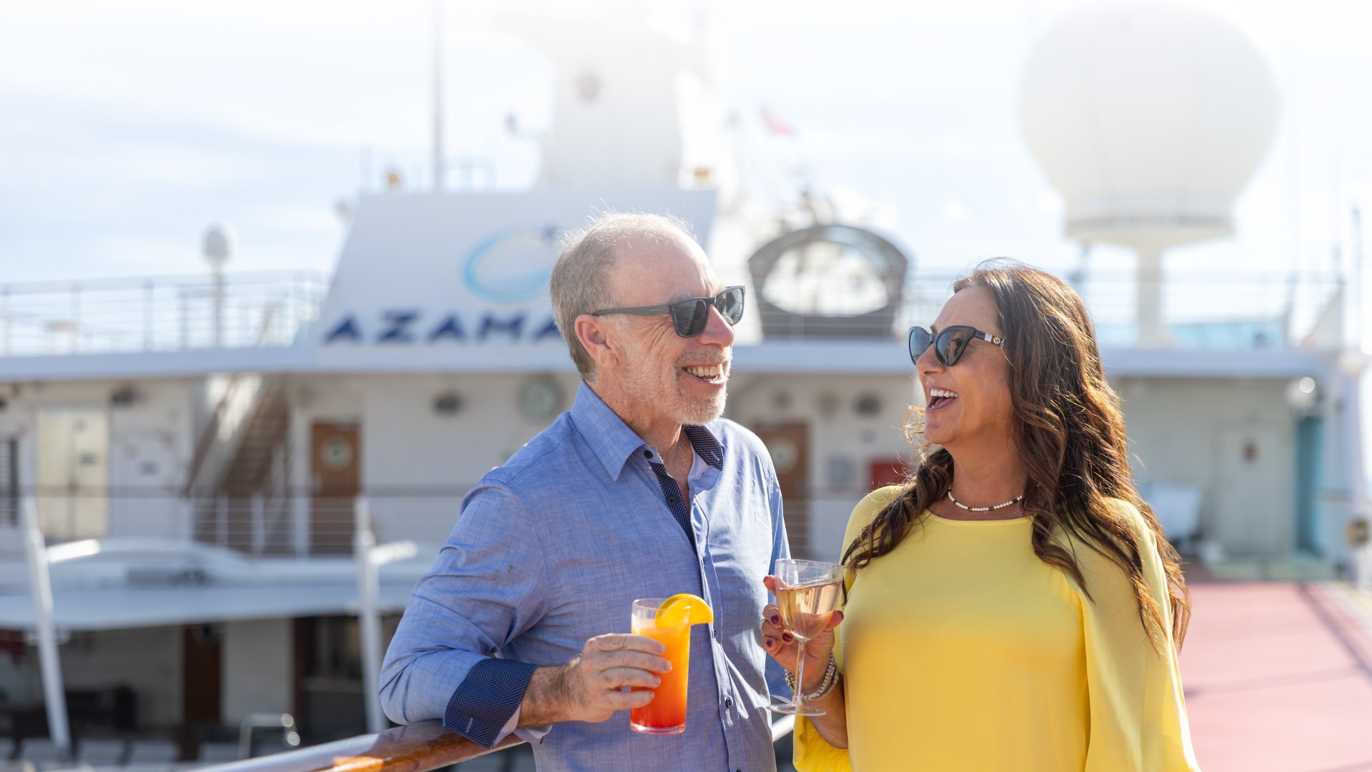 Couple smiling and enjoying drinks on a sun lit deck aboard Azamara Cruises ship!'carousel'