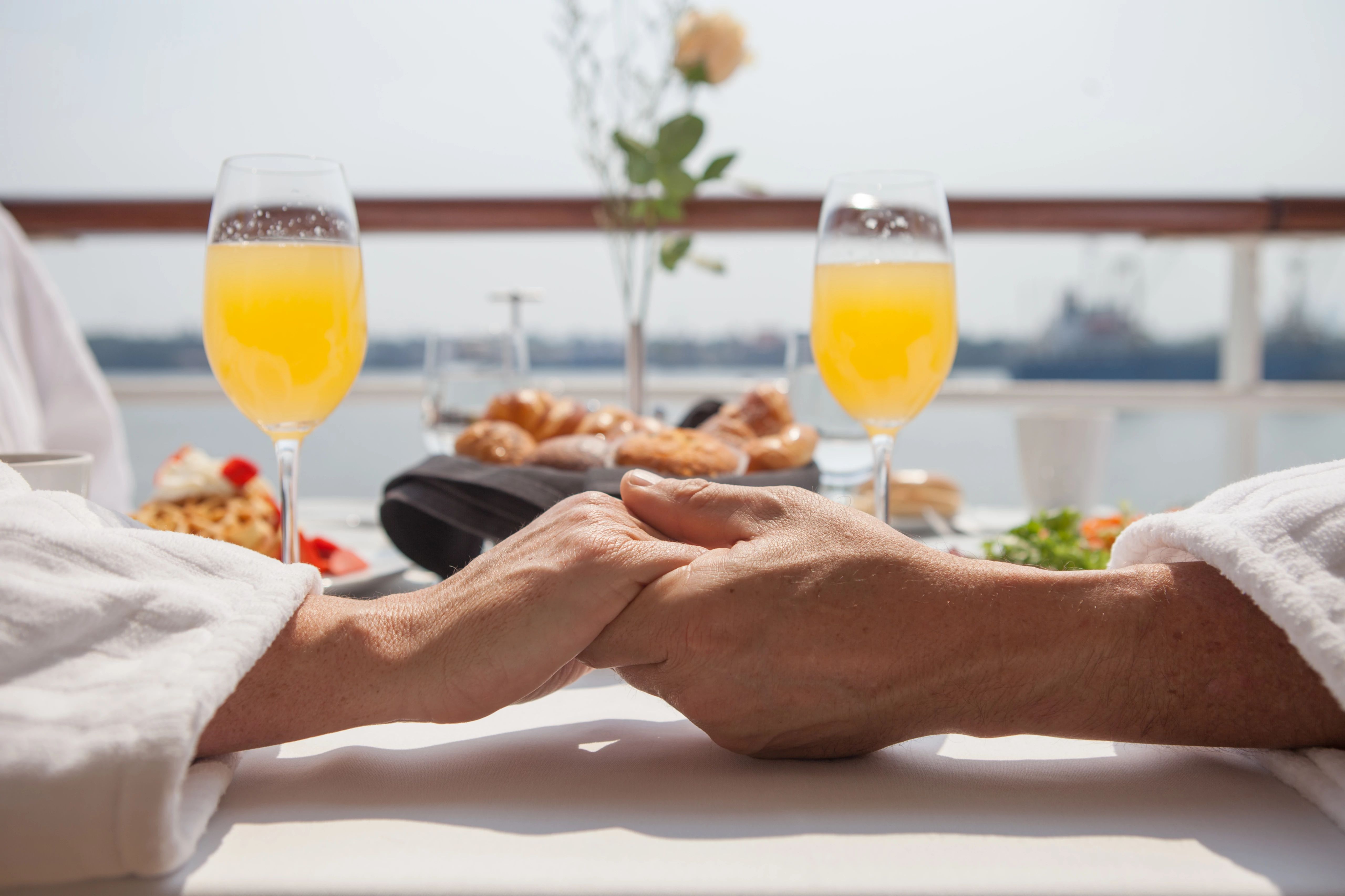 couple holding hands on balcony with drinks