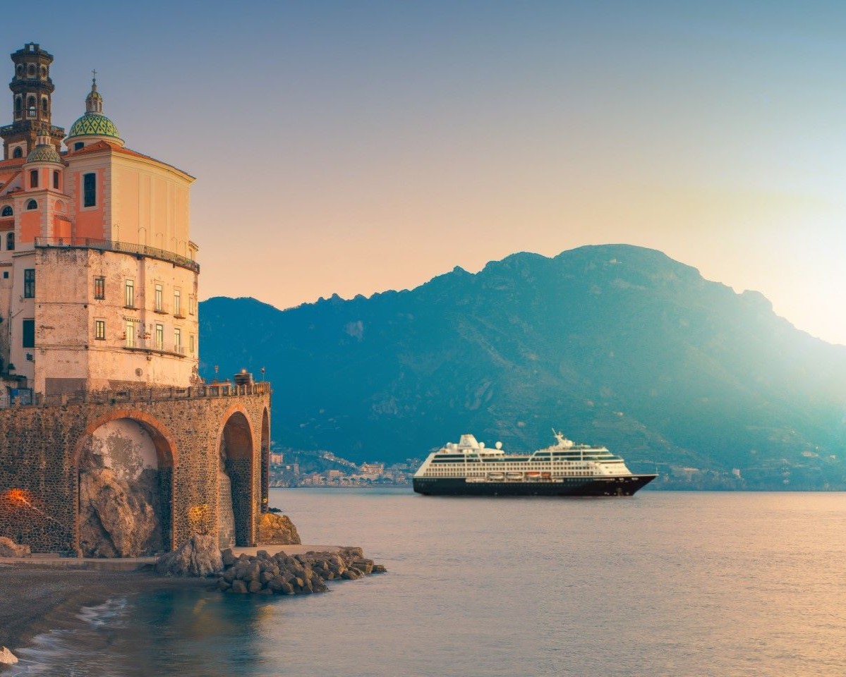 cruise ship sailing into european port at sunset